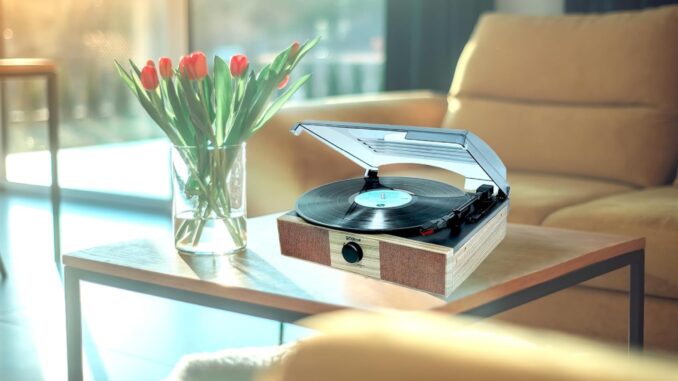 A very unconvincing image showing the Groov-e Vintage Turntable next to tulips on a wooden coffee table.