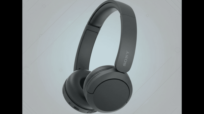 A pair of dark gray Sony over-ear headphones with a red accent on the left earcup, presented on a professional flat design background with subtle light gray patterns and gradients.
