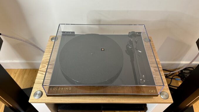 Goldring GR3 turntable, with the dustcover closed, as part of a sound system setup on a wooden surface